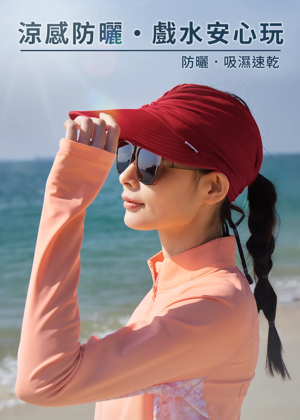 UV100抗UV-涼感戲水彈性造型空心帽赤紅色。模特兒戴墨鏡在海灘展示涼感防曬、戲水安心玩機能,呈現帽頂抽縐設計、中空帽頂保護髮型與綁帶調節彩色織繩細節,體現吸濕速乾效果。