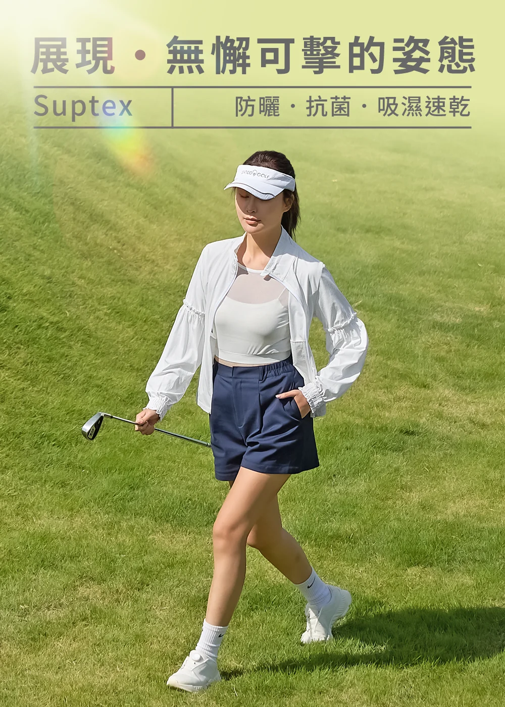 UV100 GOLF 女款 Suptex 涼感防曬外套,具備抗菌與吸濕速乾功能。模特兒穿著白色防曬外套與深藍色高爾夫短褲,展現優雅的高爾夫運動休閒穿搭。