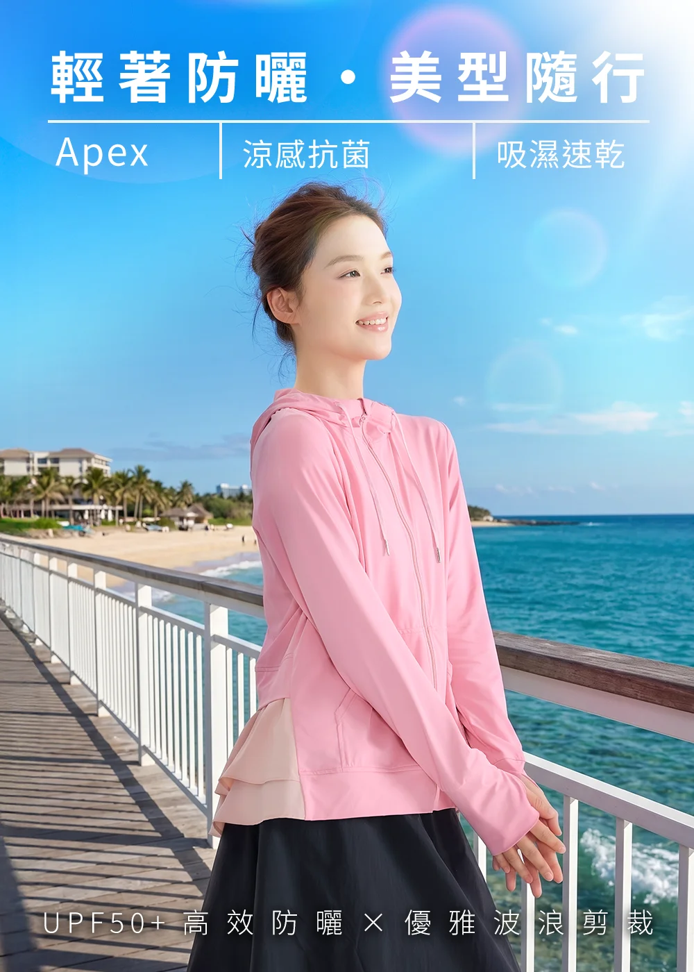 輕著防曬機能衣:女性配戴粉色波浪後擺防曬外套,在晴朗海邊步道展現 UPF50+ 高效防曬、涼感抗菌與吸濕速乾特色。