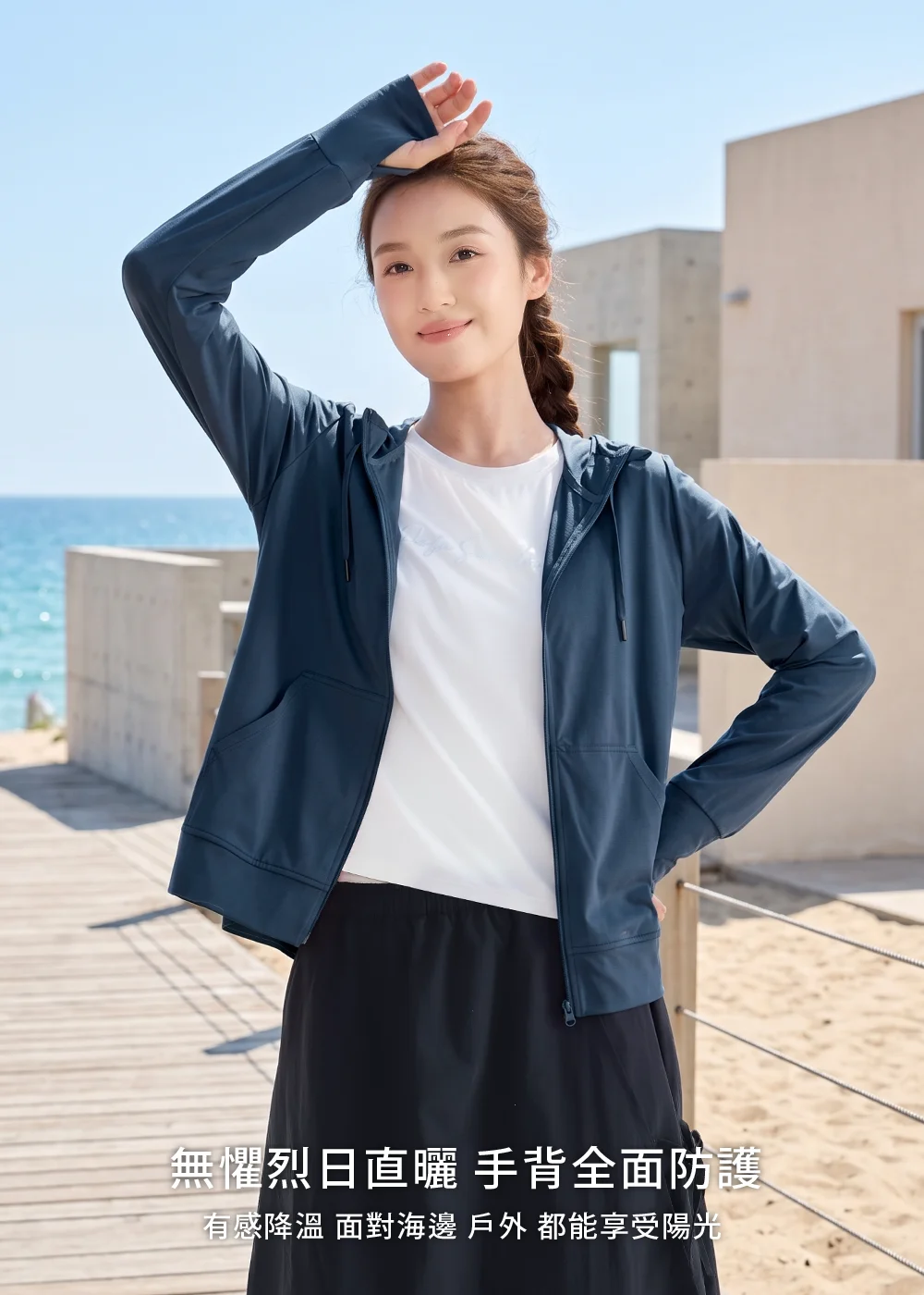 戶外休閒穿搭:女性身穿深藍色連帽防曬外套,搭配手背全面防護設計,展現無懼烈日直曬的有感降溫海邊機能防曬。