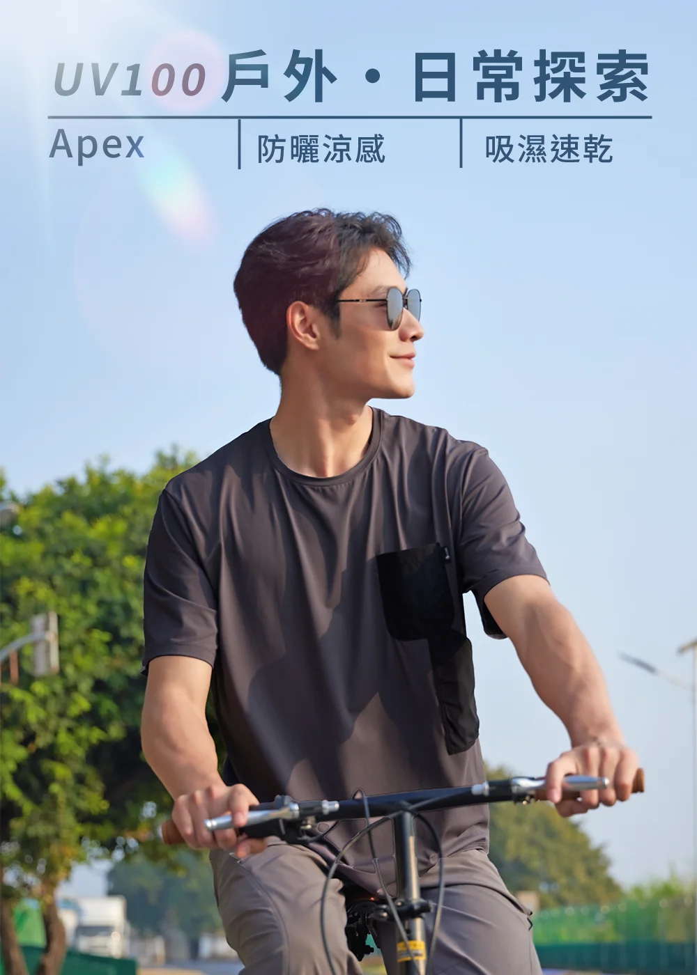 男模特兒穿著 UV100 Apex 防曬涼感、吸濕速乾短袖T恤,騎著自行車在戶外探索,展示夏日休閒時尚與功能性穿搭