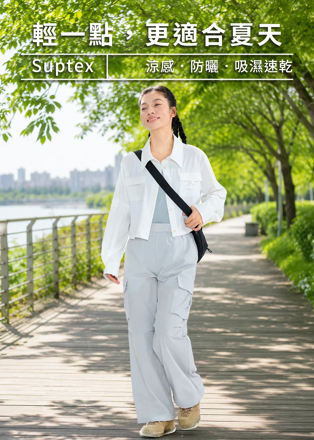 女生穿著白色UV100女款抗UV涼感短版襯衫,在晴天公園步道上散步,吸濕速乾透氣布料,適合夏季通勤與戶外防曬穿搭。