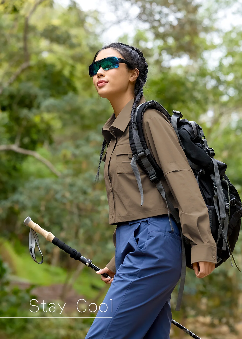 女性登山者穿著大地色抗UV防曬襯衫戶外健行穿搭,持登山杖在森林中健行,涼感透氣機能布料適合登山健走與夏季輕戶外活動。