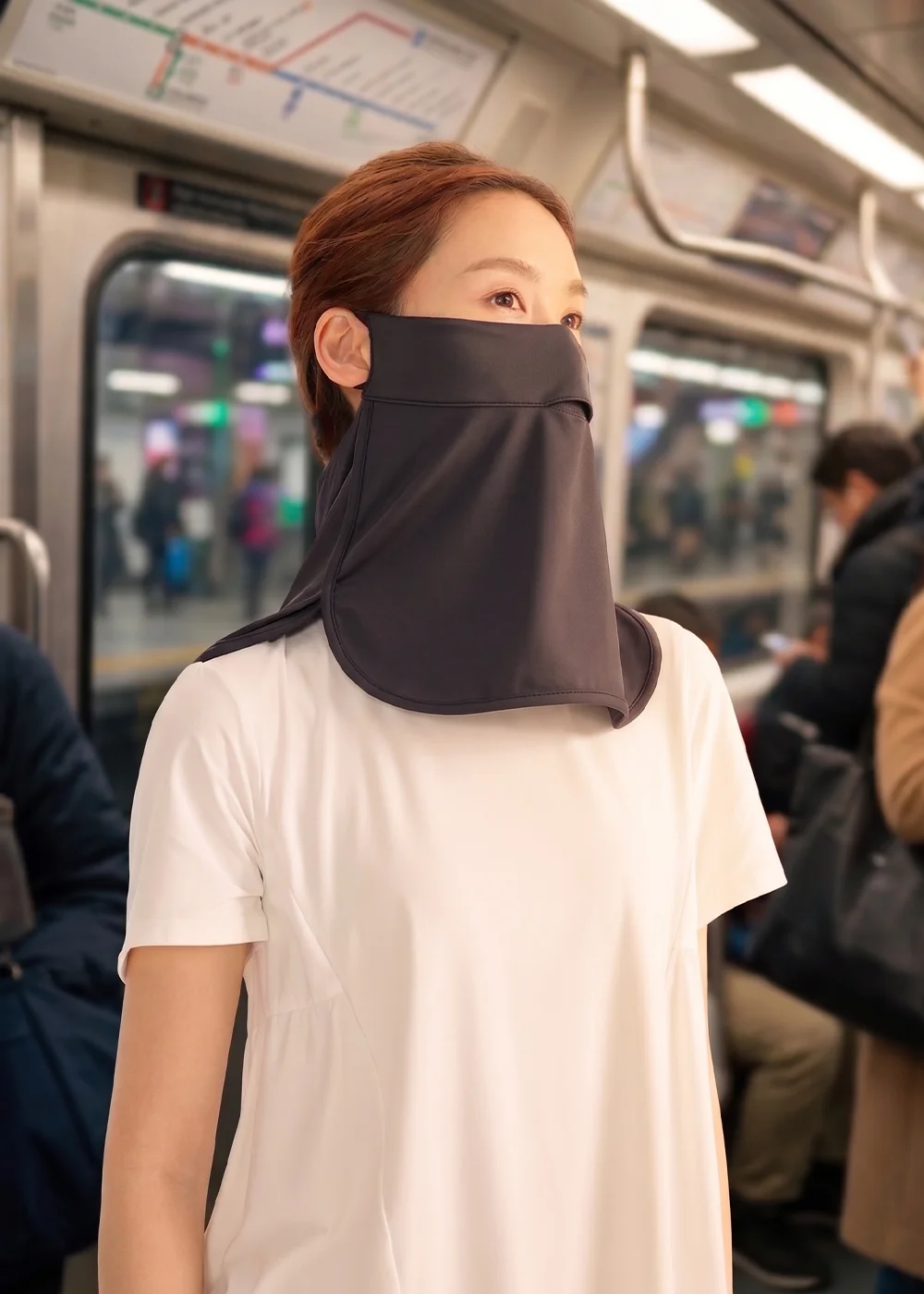 女性模特兒於捷運車廂配戴UV100黑色防曬涼感面罩,展示日常通勤物理防曬穿搭與口鼻包覆效果