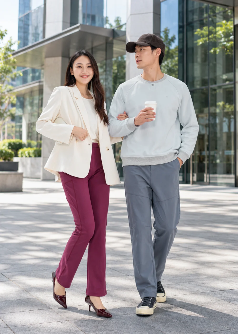 都會男女情侶通勤穿搭展示,男士穿淺灰科技羊毛長袖衛衣與休閒褲漫步商務街景