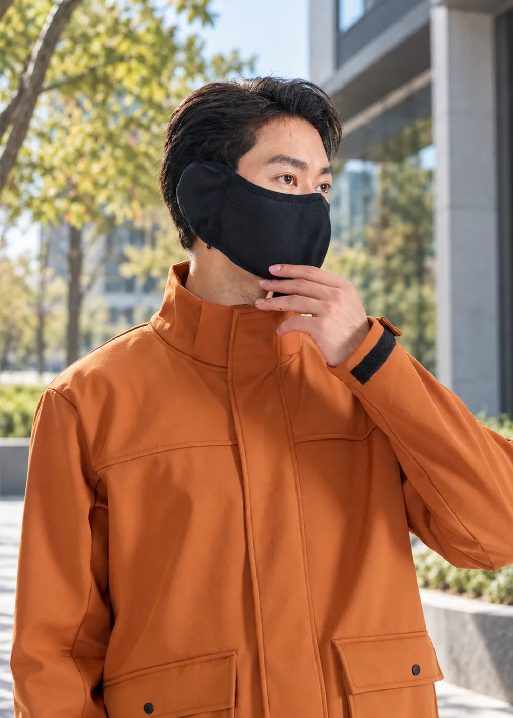 穿著橘色機能外套的男性模特兒配戴黑色耳罩式防寒面罩,手調面罩展示耳部完全包覆效果