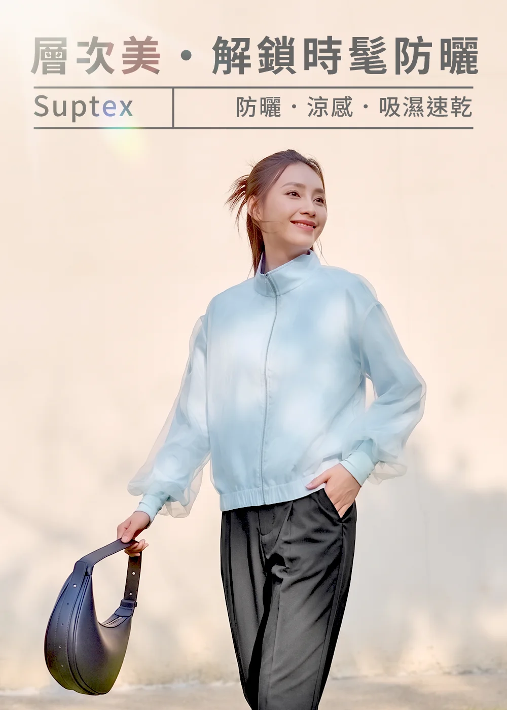 Suptex 時髦防曬外套,女性模特兒身穿防曬涼感、吸濕速乾的薄紗層次感外套(水藍),手持時尚手提包,展現層次美與仙氣視覺的都會穿搭。
