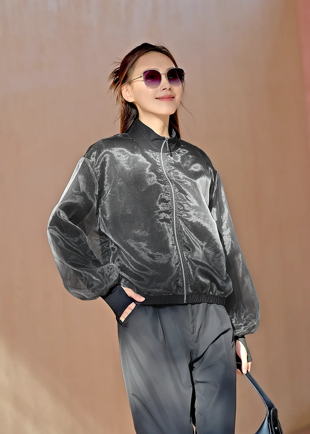 女性模特兒配戴墨鏡,身穿 Suptex 時髦防曬薄紗外套(黑),詮釋帥氣都會風格。柔光薄紗層次設計,兼具防曬與透氣舒適。