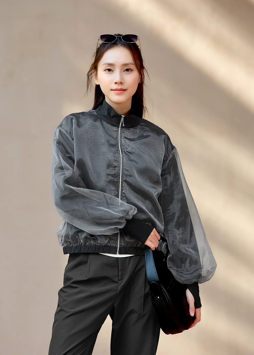 都會女性手持時尚黑包,穿著 Suptex 黑色機能防曬薄紗外套,展現俐落自信。仙氣薄紗層次美,解鎖都會女性防曬新穿搭。