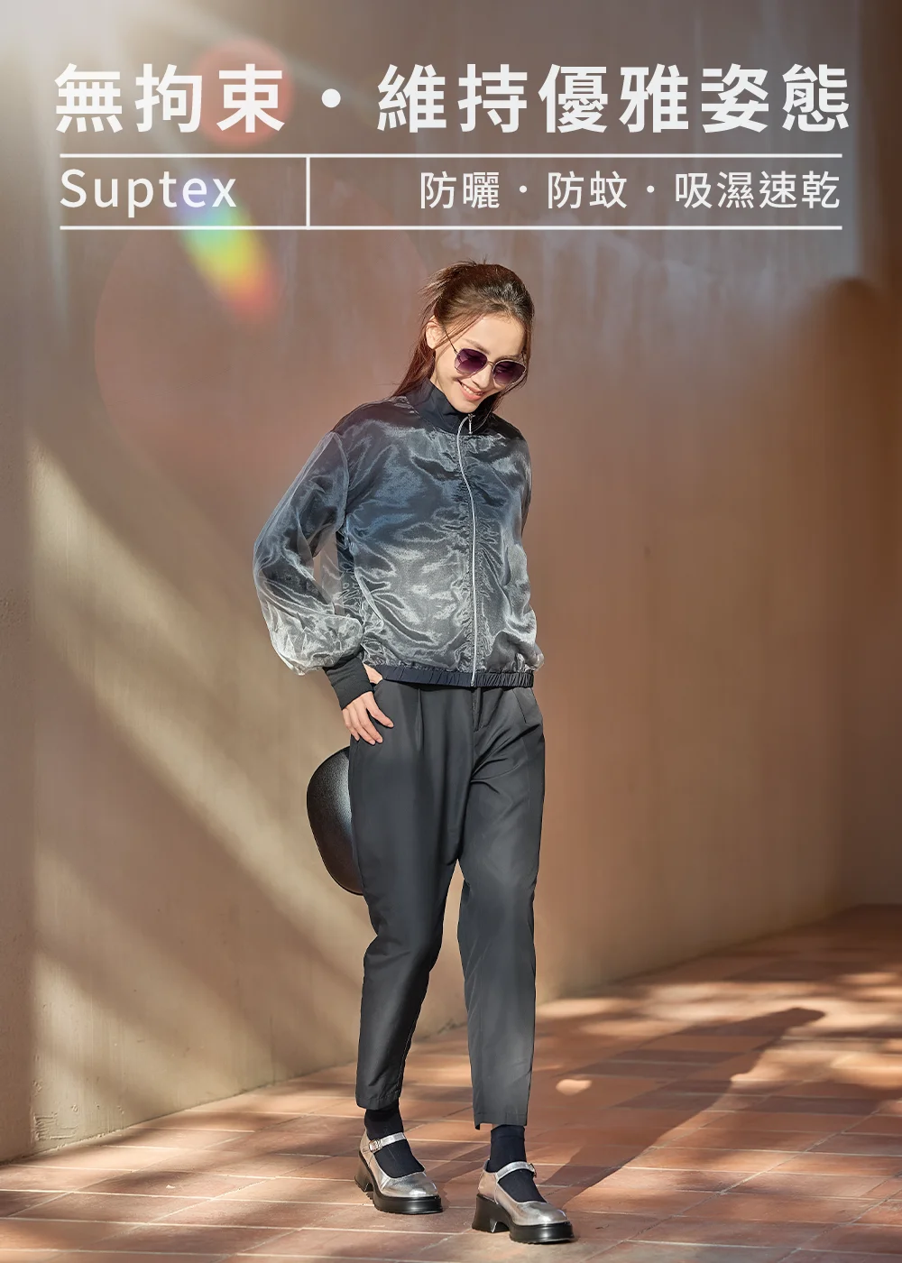 UV100 Suptex 機能防曬衣穿搭:女模特兒戴墨鏡示範黑色透膚歐根紗防曬外套與黑色修飾長褲,展現『無拘束·維持優雅姿態』的防蚊吸濕速乾休閒風格。