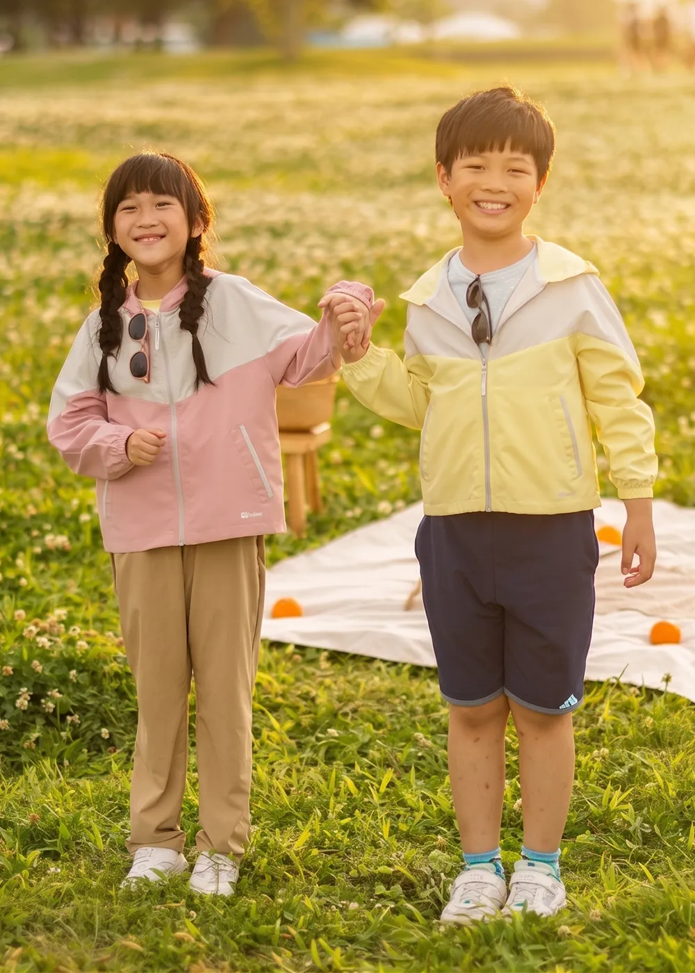 男童穿著拼色運動防曬上衣與機能防曬短褲長褲，在黃昏陽光下的戶外綠地休閒野餐
