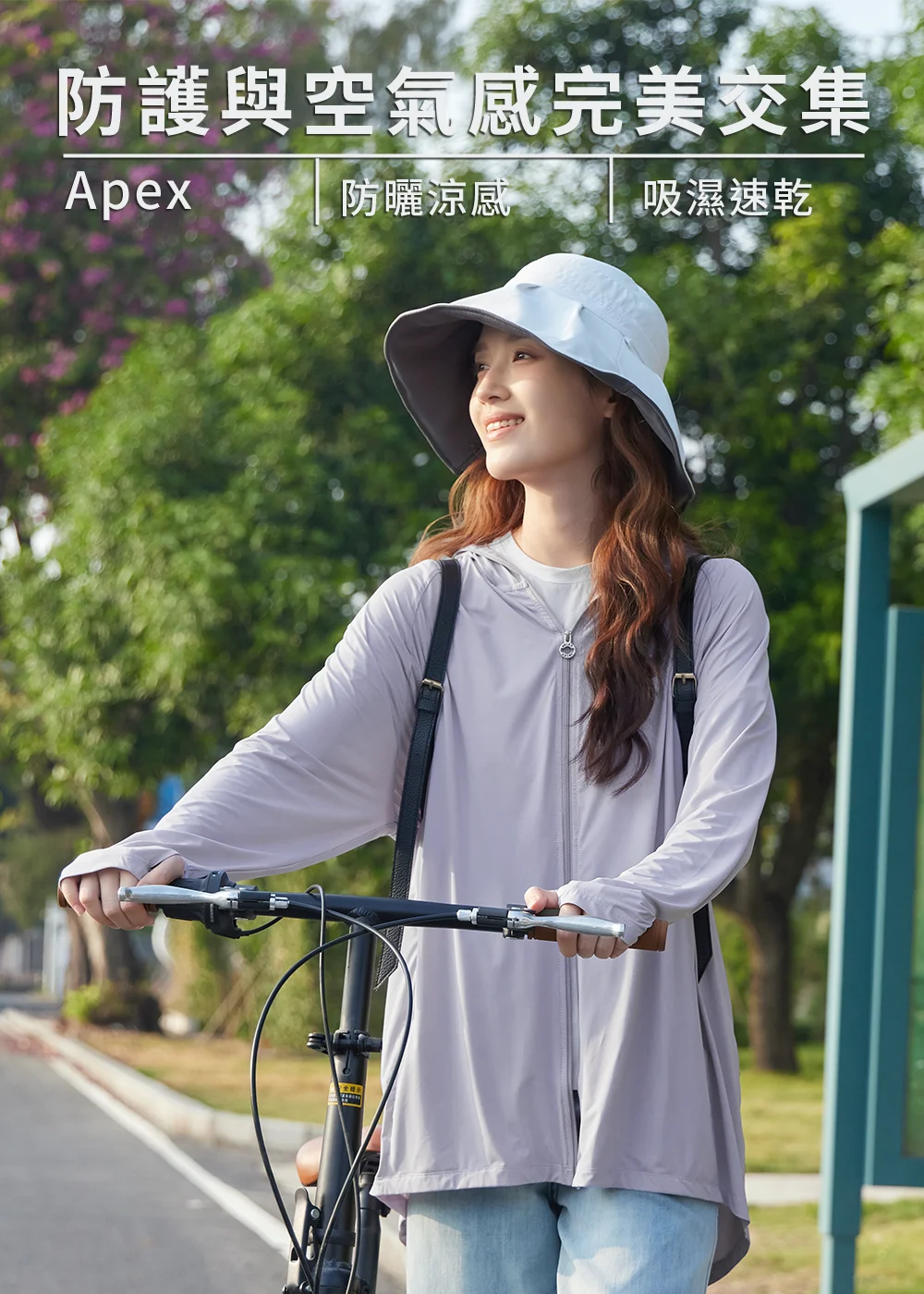 紫機能衣搭配大沿遮陽帽，女子手扶軍綠摺疊車，在陽光斑駁的林蔭下遠眺。