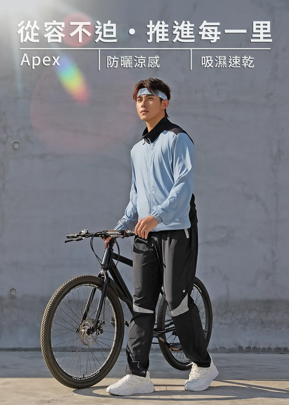 UV100 男款 Apex 系列防曬涼感機能外套，適合都市騎行，具備吸濕速乾與防曬涼感功能，模特兒於陽光下牽單車展現休閒運動風。