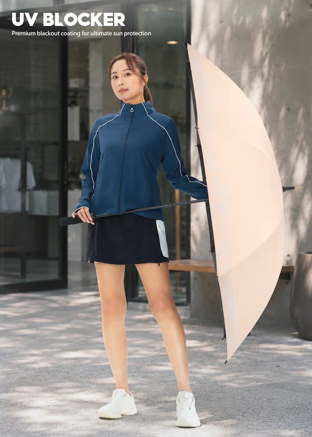 女模特兒在戶外建築前手持 粉膚色款幾何大傘面晴雨兩用直傘，展現 34 吋大傘面的流線設計與俐落外型，呈現女性都會通勤的時尚防曬視覺。