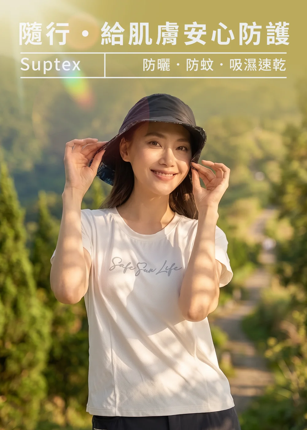 女模特兒戴著 UV100 Suptex 雙面花色防曬防蚊遮陽帽，搭配白色「Safe Sun Life」印花短袖T恤，在戶外綠意景致中展示「隨行・給肌膚安心防護」的夏日健行穿搭