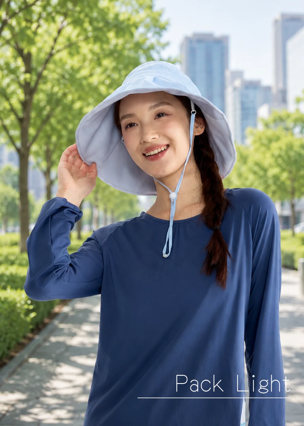 女生配戴淺藍色抗UV造型防曬帽，防風繩防落設計搭配涼感防曬上衣，適合通勤散步與城市休閒活動。